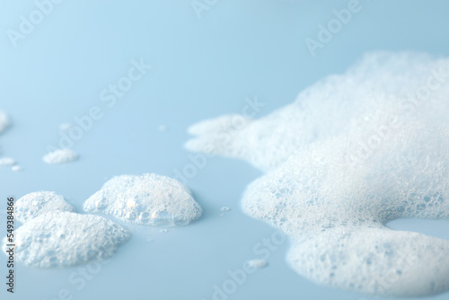 Fluffy bath foam on light blue background, closeup