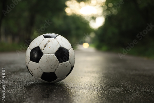 Dirty leather soccer ball on wet road, space for text © New Africa