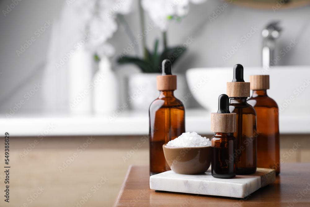 Essential oils and sea salt on wooden table in bathroom. Space for text Essential oils and sea salt on wooden table in bathroom. Space for text