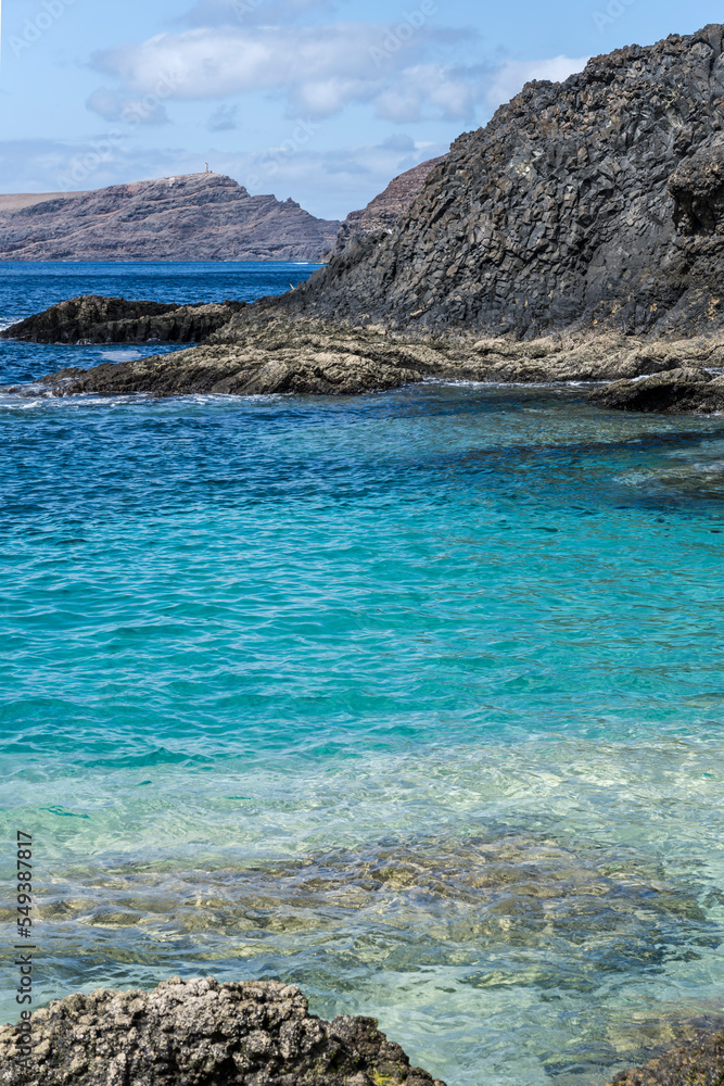  clear blue ocean waters and volcanic cliffs at Calheta cape, Porto Santo island