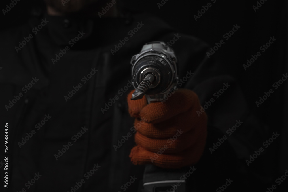 Hand holds cordless electric screwdriver with bit for screws and drilling isolated on black background Hand holds cordless electric screwdriver with bit for screws and drilling isolated on black background
