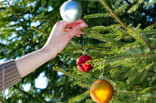 A girl hangs Christmas balls on the Christmas tree. New Year's background.