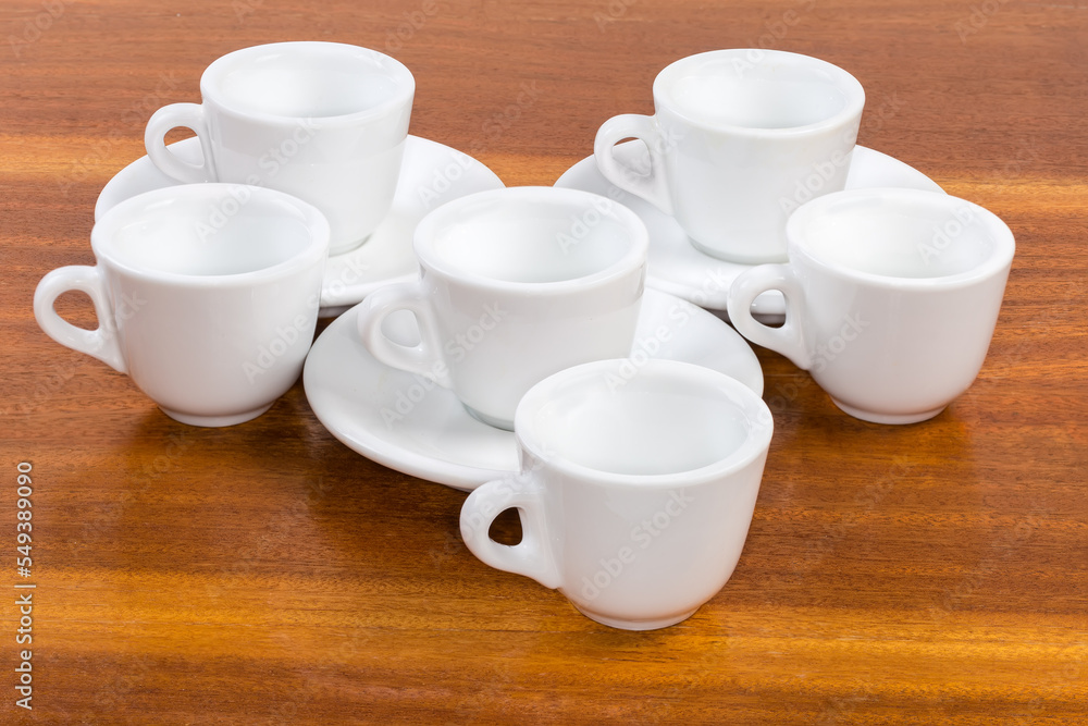Small empty white coffee cups and saucers on wooden surface Small empty white coffee cups and saucers on wooden surface