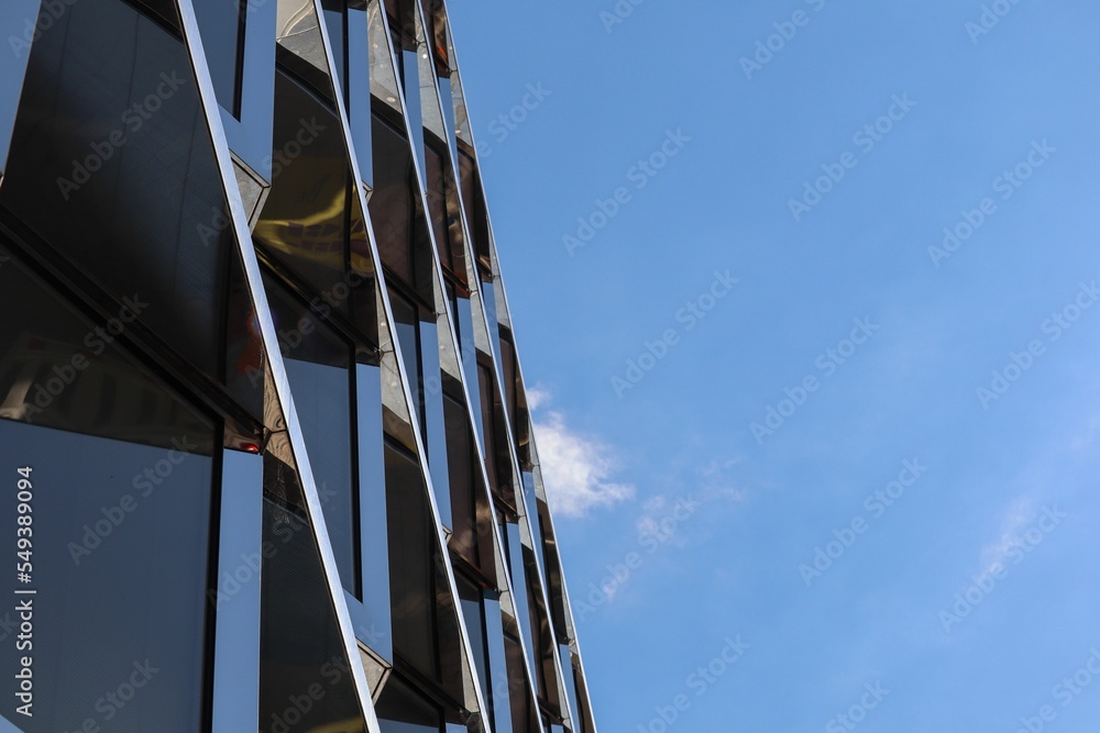 Naklejka premium Low angle of a modern glass building under a blue sky in Berlin, Germany.