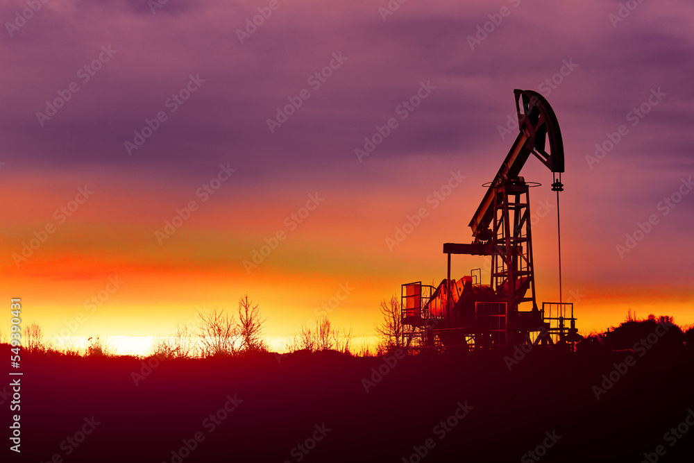 Oil pumps at sunset, industrial oil pumps equipment. Sunset and darkness. Oil field in the fog. Red toned Abstract image. Crisis in the oil production industry dramatic concept.
