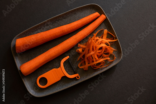 Two peeled carrots ondark background photo