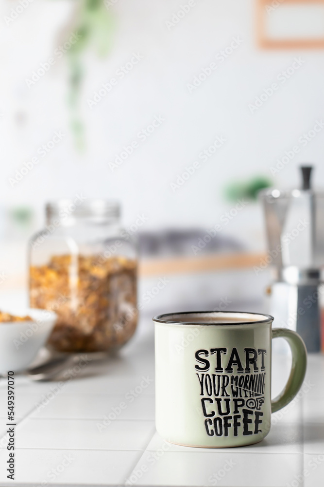Mug of morning coffee on white tile tabletop in kitchen. Healthy breakfast consept with coffee and muesli. Text space Mug of morning coffee on white tile tabletop in kitchen. Healthy breakfast consept with coffee and muesli. Text space