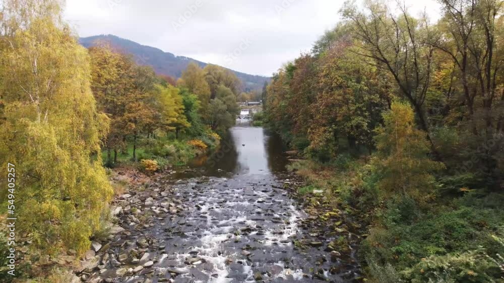Aerial perspective shot of a calm river flowing at its own pace with colourful woodland adorning the river. Untouched nature. 4k video