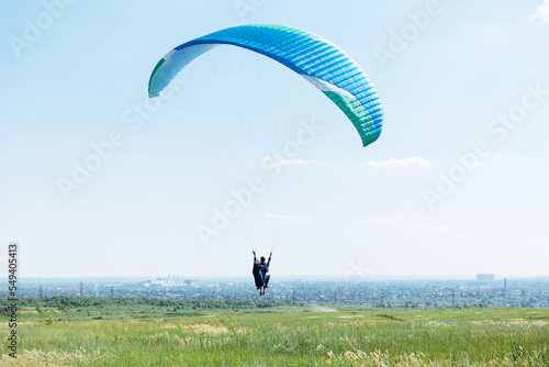 Blue Paraglider flying into the sky with clouds on a sunny day