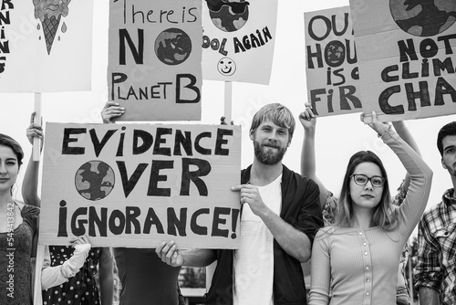 Young group of demonstrators on road from different culture and race protest for climate change - Focus on center guy face - Black and white editing