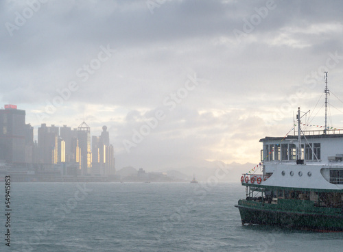 Photography Star ferry crossing Kowloon Bay / Hong Kong Harbour in rain to destination of sunlit skyscrapers