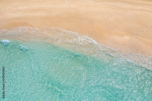 Summer seascape beautiful waves  blue sea water in sunny day. Top view from drone. Sea aerial view  amazing tropical nature background. Beautiful bright sea waves splashing and beach sand sunset light