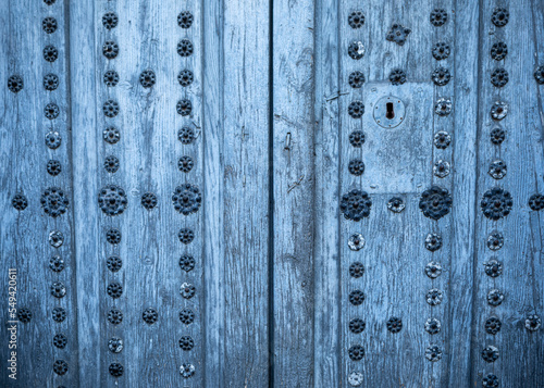 Old aged two-leaf door with metal decorations in natural wood of blue-gray color