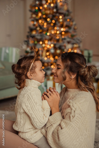 Happy New Year! family traditions. young mother and her daughter have fun at home near the Christmas tree and fireplace