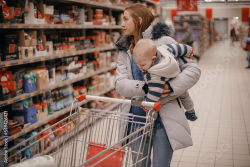 Shopping with kids. Mother and child buying in supermarket. Mom and her little son are in a grocery store shopping for food © ibilyk13