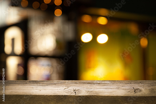 Image of wooden table in front of abstract blurred lights of cafe restaurant
