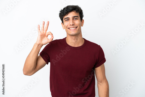 Young Argentinian man isolated on white background showing ok sign with fingers