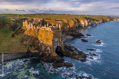 Aerial view with Dunluce Castle, the famous fortress in ruin in Northern Ireland UK, seen at sunrise