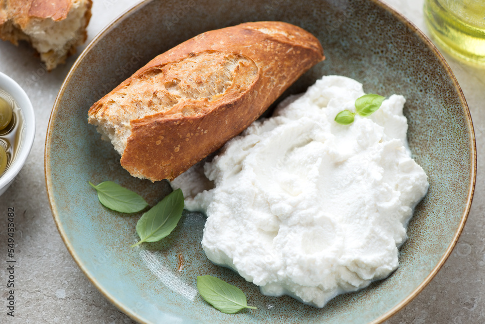 Rustic plate with italian ricotta cheese and crusty baguette, middle close-up, horizontal shot, selective focus Rustic plate with italian ricotta cheese and crusty baguette, middle close-up, horizontal shot, selective focus