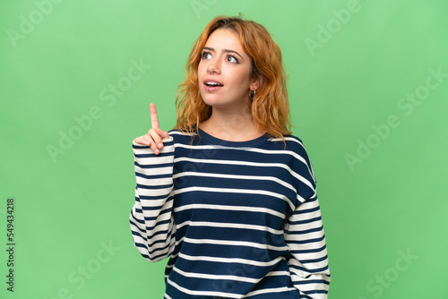 Young caucasian woman isolated on green screen chroma key background thinking an idea pointing the finger up