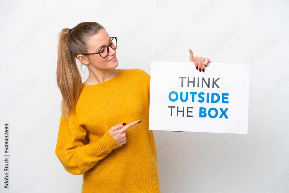 Young caucasian woman isolated on white background holding a placard with text Think Outside The Box and pointing it Young caucasian woman isolated on white background holding a placard with text Think Outside The Box and pointing it