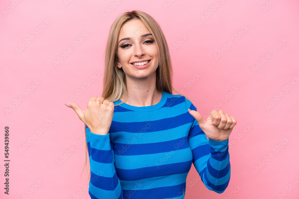 Pretty blonde woman isolated on pink background pointing to the side to present a product Pretty blonde woman isolated on pink background pointing to the side to present a product