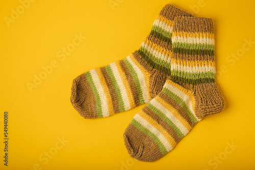 Bright handmade socks on a yellow background.Knitted warm winter socks. Wool yarn. winter hobbies. Hobby.Place for text, space for copy.