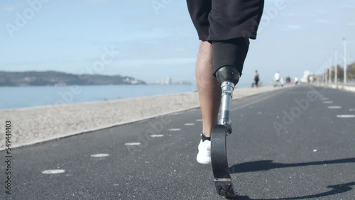 A man running with a prosthetic leg by the beach photo