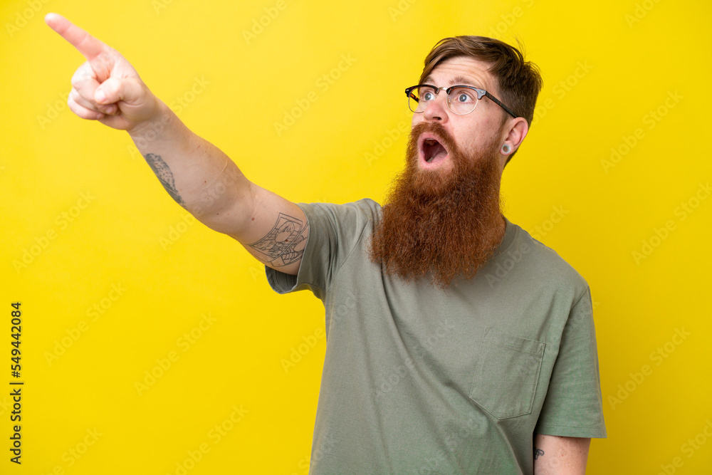 Redhead man with beard isolated on yellow background pointing away Redhead man with beard isolated on yellow background pointing away