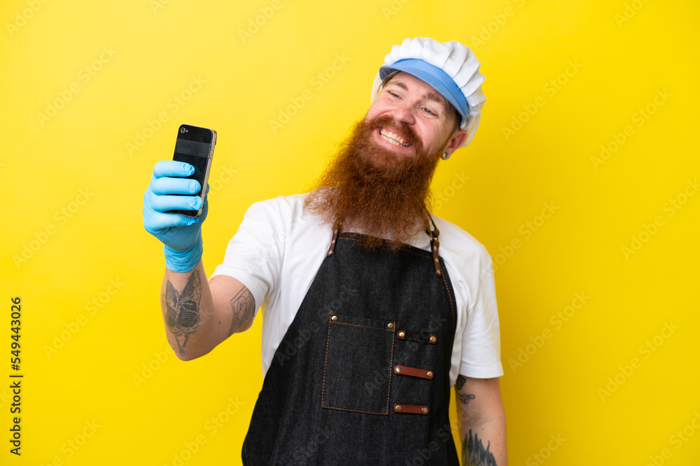 Fishmonger wearing an apron isolated on yellow background making a selfie Fishmonger wearing an apron isolated on yellow background making a selfie