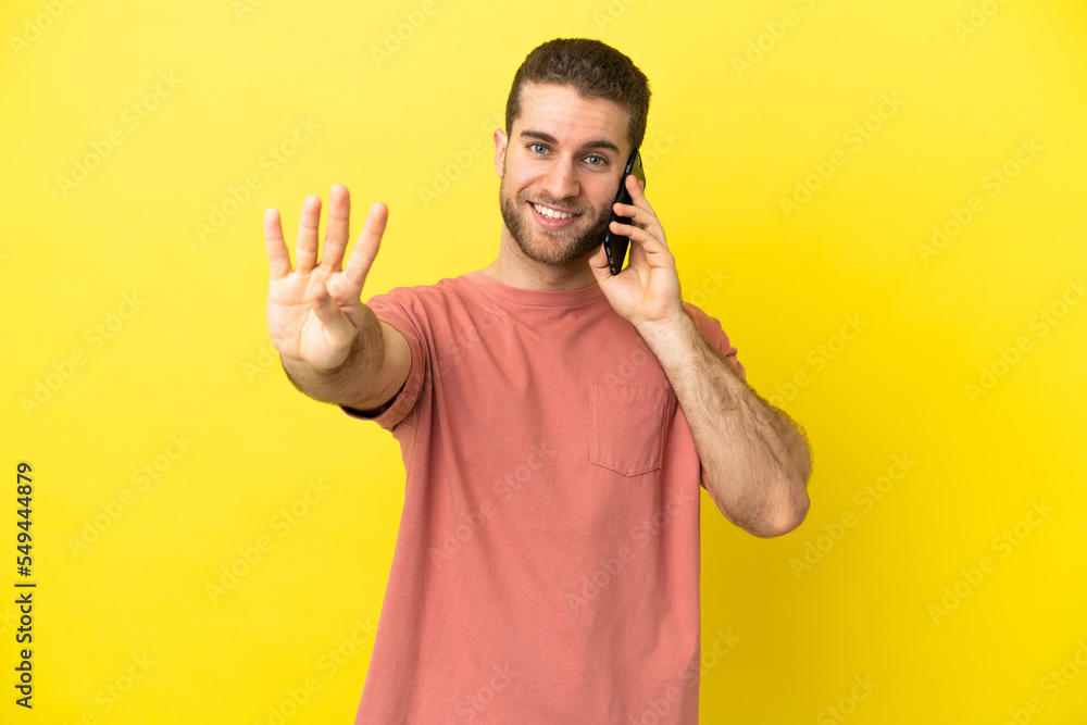 Handsome blonde man using mobile phone over isolated background happy and counting four with fingers Handsome blonde man using mobile phone over isolated background happy and counting four with fingers