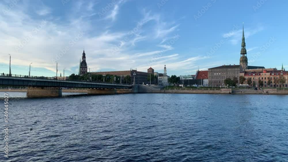 Panoramic view of Riga city skyline from moving boat. St. Peter's Church tower and Cathedral tower in the background. Sunny summer day. Riga, Latvia Panoramic view of Riga city skyline from moving boat. St. Peter's Church tower and Cathedral tower in the background. Sunny summer day. Riga, Latvia