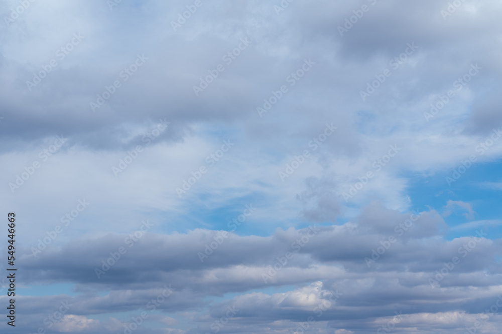 Lots of cumulus clouds far on horizon on blue daylight sky. Light blue sky with clouds, fresh atmosphere. White fluffy clouds running across a sunny blue sky. Wonderful summer air