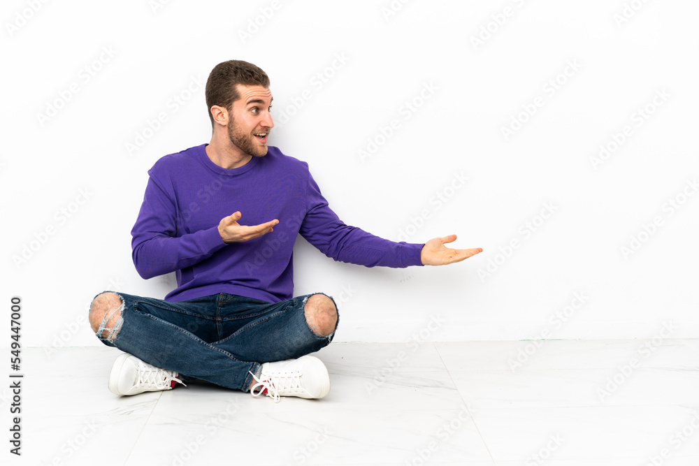 Young man sitting on the floor with surprise expression while looking side