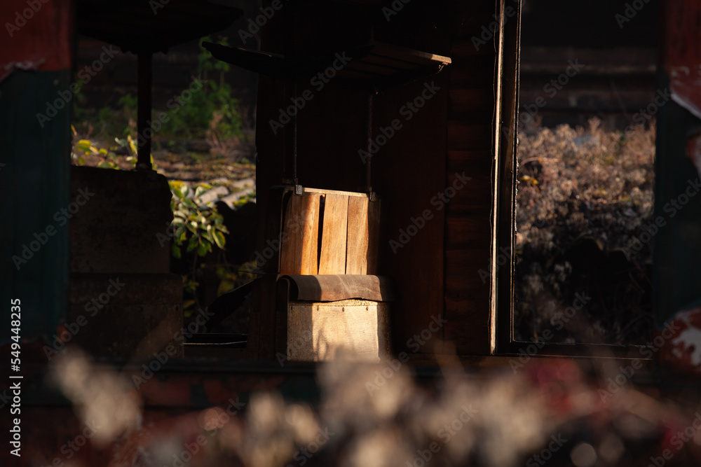 Obraz premium An abandoned train seat in a carriage. A wooden bench is lit by a ray of sunlight. the wagon is abandoned, there are no more windows or doors.