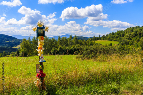 Fototapeta Naklejka Na Ścianę i Meble -  Wayside catholic cross on countryside rural road in Beskidy Mountains on sunny summer day near Zywiec, Poland