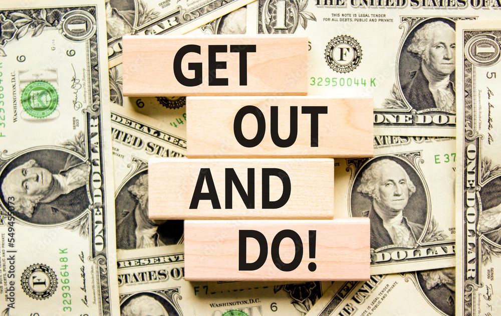 Motivational get out and do symbol. Concept words Get out and do on wooden cubes. Beautiful background from dollar bills. Business motivational get out and do concept. Copy space.