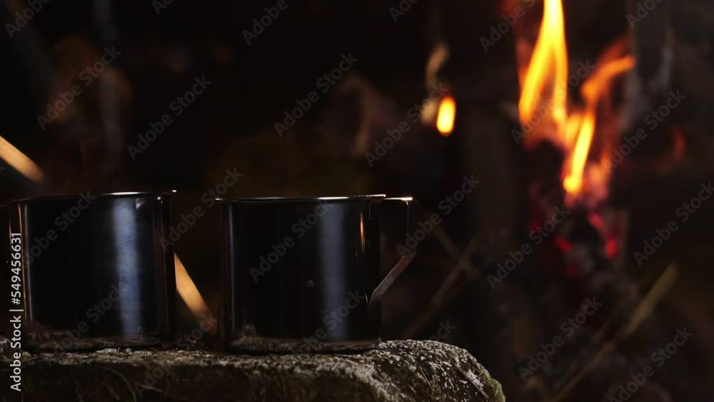 Seniors camping at night, resting on his winter vacation, a mug of warm water, around a campfire Seniors camping at night, resting on his winter vacation, a mug of warm water, around a campfire