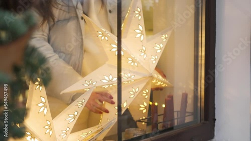 Building front decorated to Christmas with christmas trees fir branches, decorations and garland lights. Two big windows decorated for winter holidays.