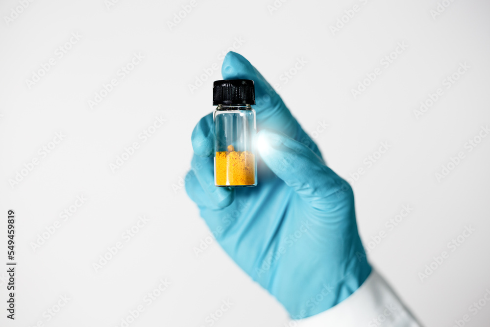 Close up of Scientist hand shows an orange solid in vial glass of curcumin compound from extraction and isolation in laboratory. Curcumin substances are used for pharmaceuticals, medicine. Close up of Scientist hand shows an orange solid in vial glass of curcumin compound from extraction and isolation in laboratory. Curcumin substances are used for pharmaceuticals, medicine.