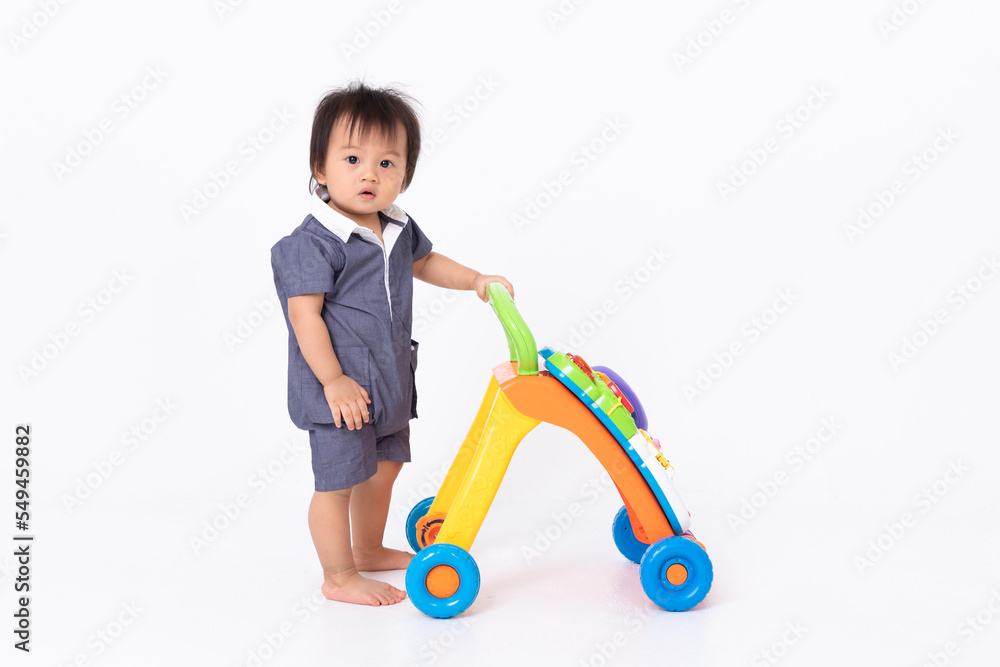 Little Asian baby boy stand up with toy walker for support and help to walking isolated on white. Happy Toddler looking at camera and holding stand learning walker. Develop and growth baby. Baby care Little Asian baby boy stand up with toy walker for support and help to walking isolated on white. Happy Toddler looking at camera and holding stand learning walker. Develop and growth baby. Baby care