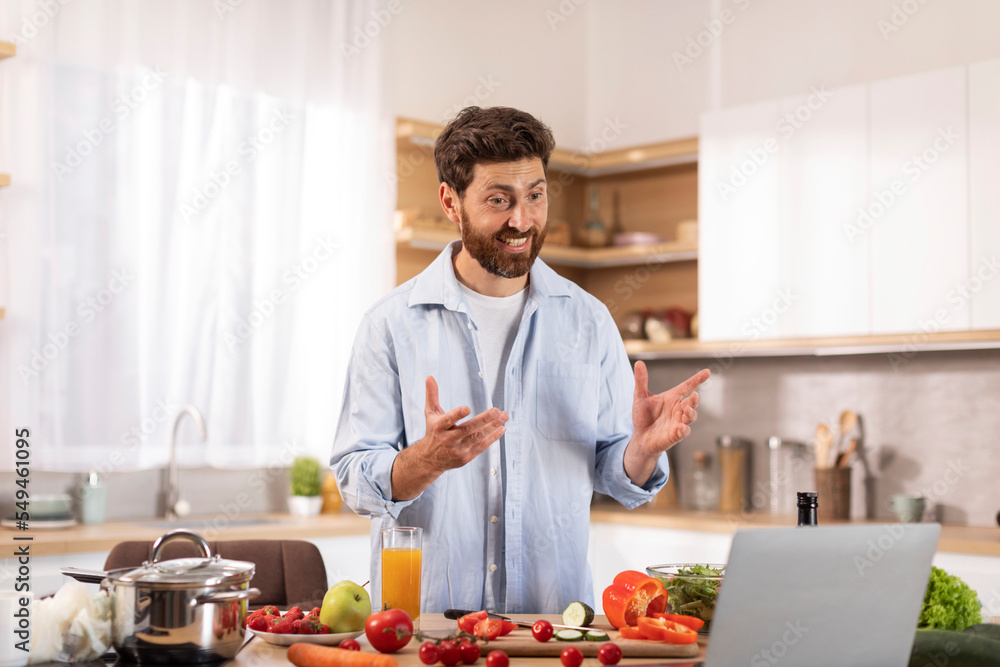 Cheerful middle aged caucasian man with beard has video call, make video for food blog, gesturing hands Cheerful middle aged caucasian man with beard has video call, make video for food blog, gesturing hands