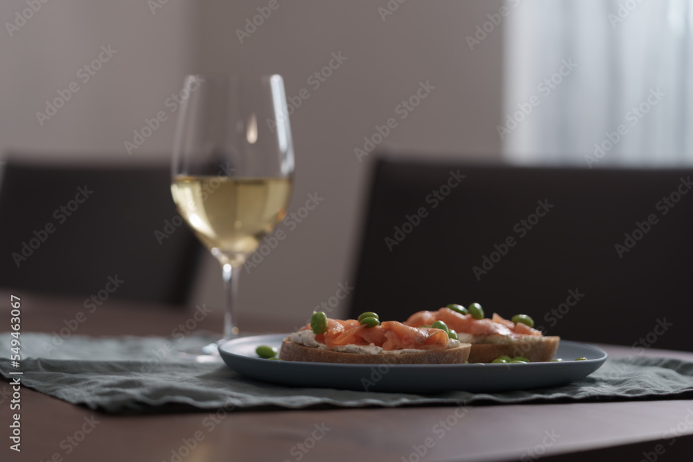 Bruschettas with cream cheese and salmon with glass of white wine on dining table