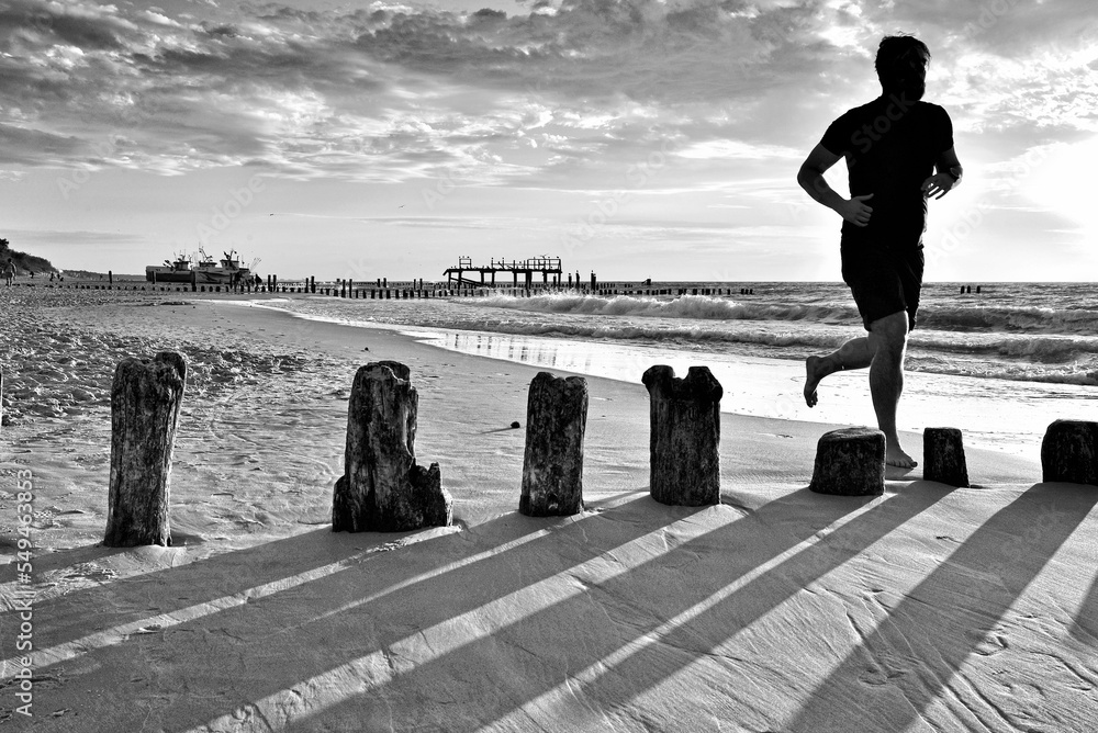 POLAND, MIELNO - CIRCA JULY 2018: A man is running along the seashore. In summer, the beach attracts many jogging enthusiasts.