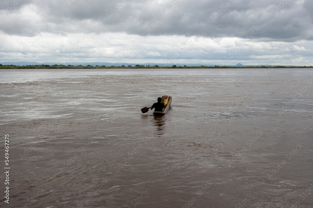 Zambezi River in Mozambique, with the silhouette of a man paddling a canoe alone Zambezi River in Mozambique, with the silhouette of a man paddling a canoe alone