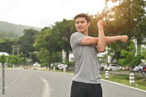 Foto Young Asian athlete fit man stretches his arm, Warm up before getting ready to work out or cool down after done, Activity healthy lifestyle concept