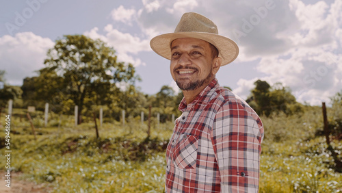 Portrait of young farmer man in the casual shirt and hat in the farm