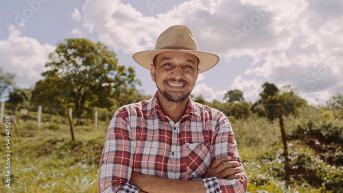 Portrait of young farmer man with crossing hands in the casual shirt and hat in the farm