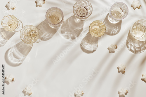 New Year holiday flat lay, white sparkling wine in crystal glasses, festive champagne drinks, Christmas bauble stars on beige background, Winter holiday celebration concept, trend still life