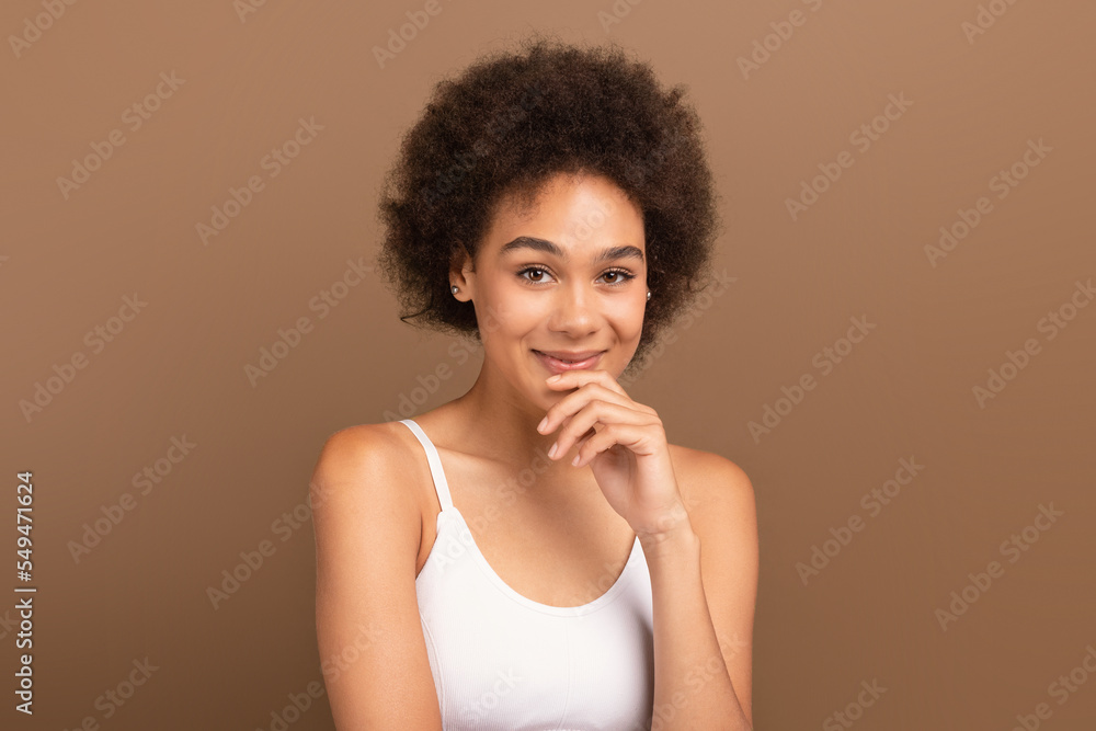 Portrait of cheerful millennial african american curly lady with perfect skin in white top look at camera Portrait of cheerful millennial african american curly lady with perfect skin in white top look at camera